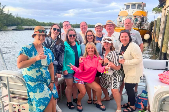 A group of people posing on a boat near the dock with smiles and casual attire.