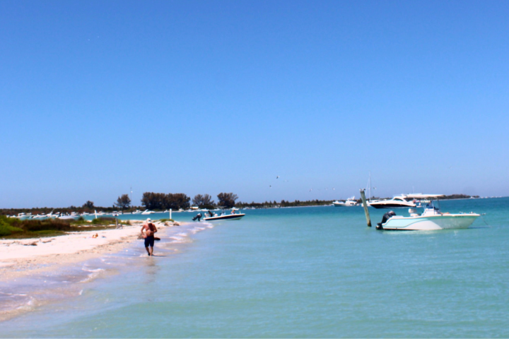 Scenic beach with people, boats, and clear blue water.