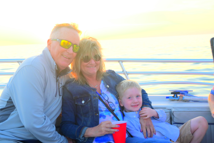 Family posing on a boat during sunset, with a child sitting on a woman's lap.
