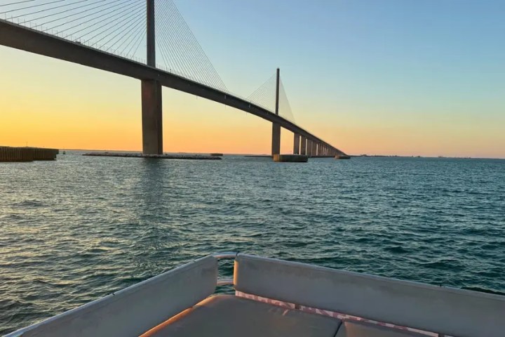 Bridge over water at sunset with view from a boat's deck.