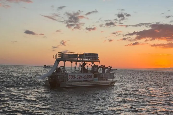 Boat with slide on sea at sunset, people on board.