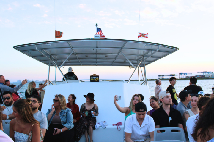 People on a boat enjoying a sunny day, with small flags above.