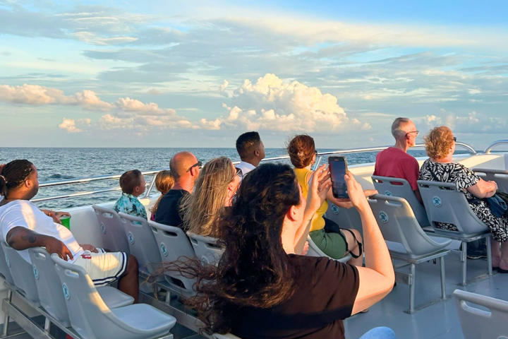 People sitting on a boat deck, enjoying the ocean view at sunset.