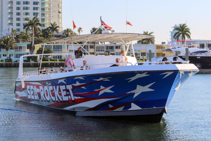 Colorful tour boat with star design docked in a tropical cityscape.