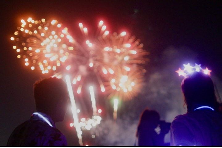 Silhouettes of people watching colorful fireworks in the night sky.