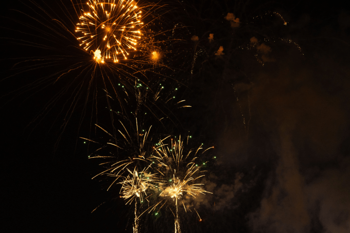 Golden fireworks bursting in the night sky with faint smoke.