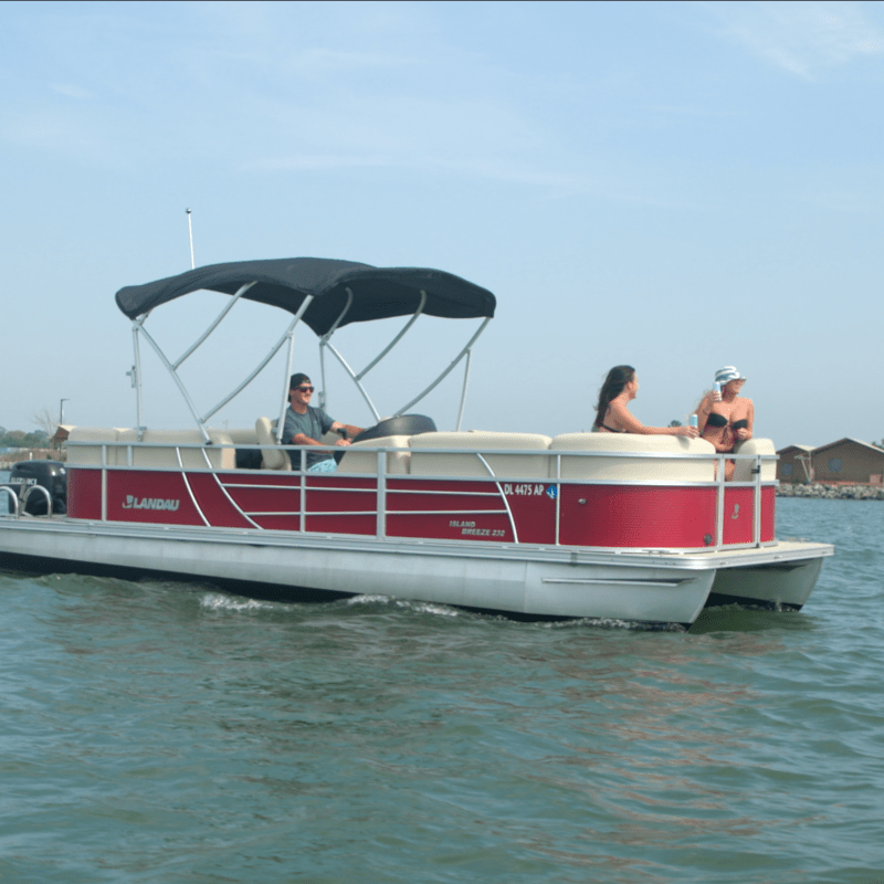 People on a red pontoon boat on a lake.